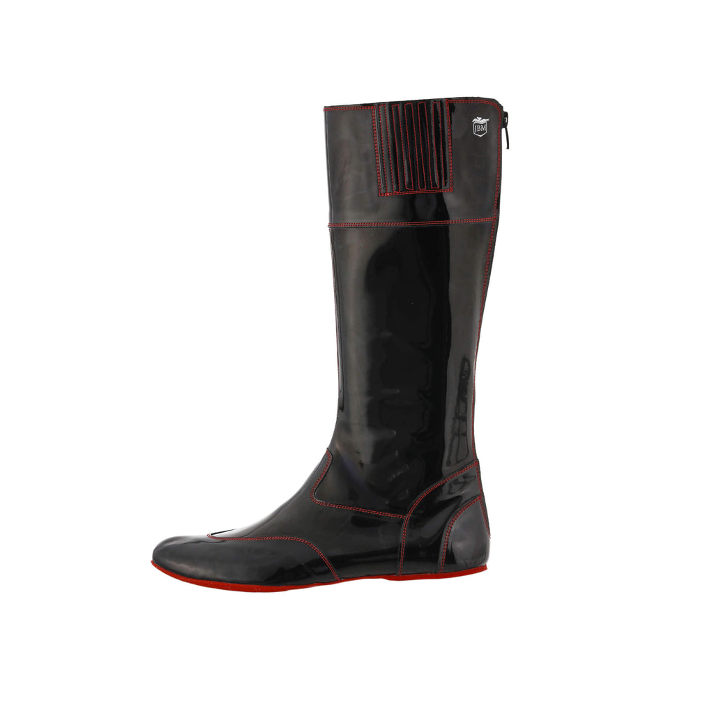 A single tall racing boot made of black material with red exterior stitching and red soles, displayed against a white background. The boot features a back zip and a 1.5-2cm stretch feature around the calf. This image only showcases the boot from a side perspective.