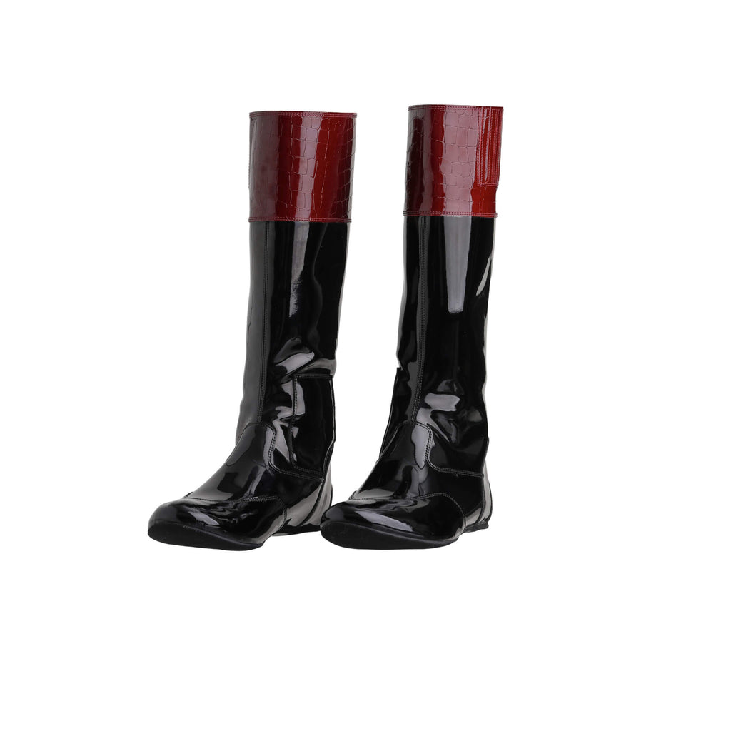 A pair of tall racing boots with black material and burgundy crocodile leather accents on the calf, displayed on a white background. The boots feature a back zip and a 1.5-2cm stretch feature around the calf. They are made of light, tough, flexible, and strong black material. Both boots are positioned sole down with the zipper done, angled slightly to one side.