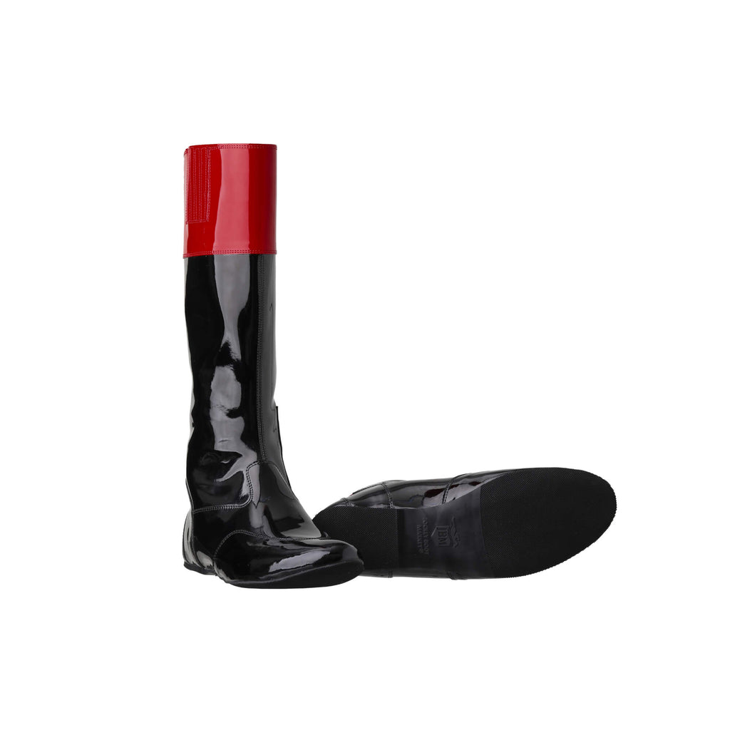 Tall racing boots with black material and red patent leather accents on the calf, displayed on a white background. The boots feature a back zip and a 1.5-2cm stretch feature on the calf area. They are made of light, flexible, and strong material. One boot is positioned sole down with the zipper done, while the other is laid down to showcase the sole.