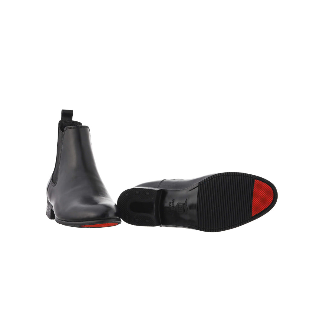 A pair of classic black short boots with a convenient slide-on design, presented against a white background. One shoe is displayed sole down, while the other is laid down to showcase the sole featuring a red tip, emblematic of their signature design.