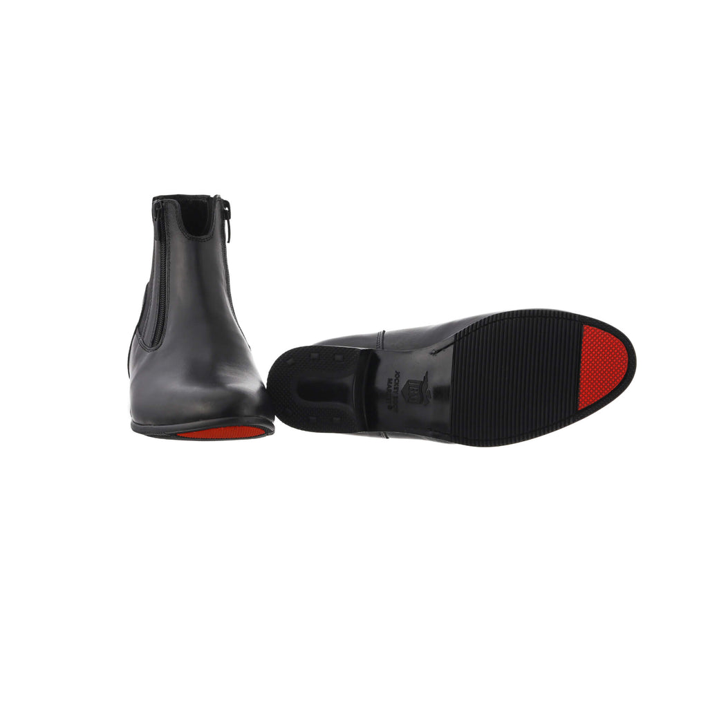 A pair of classic black short boots featuring double front zip and a gap on the top front to provide extra comfort when horse riding. Presented on a white background. One shoe is displayed sole down with zips done, while the other shoe is laid down to showcase the sole which has a red tip as their signature sole design.