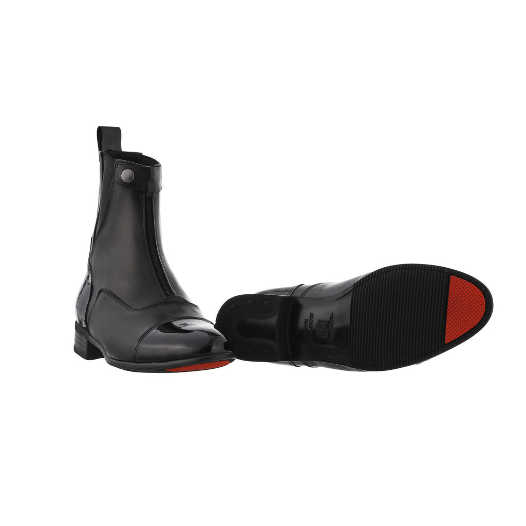 A pair of black patent toe leather boots displayed against a white background. One boot is positioned sole-down with the front zip and buckle closure completed, while the other boot is laid flat to showcase its sole, featuring a signature red-tipped design.