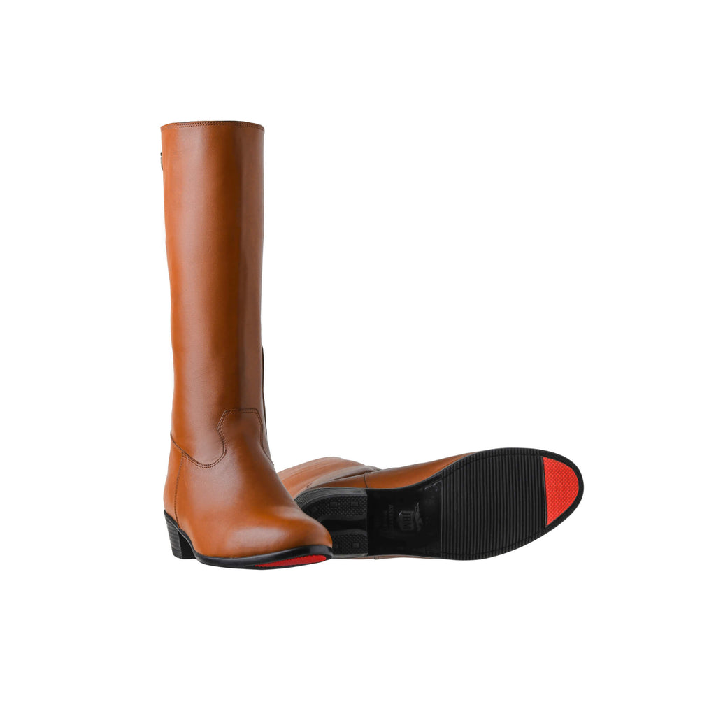 A pair of tall tan leather Cuban heel boots featuring a back zip, displayed against a white background. One boot is positioned sole down with the zipper done, while the other boot is laid down to showcase the sole featuring a red tip design.