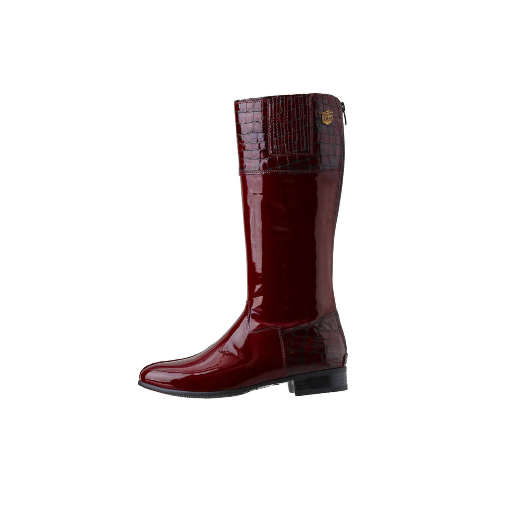 A tall burgundy patent and crocodile leather boot displayed against a white background. The boot features a back zip and a 1.5-2cm stretch feature on the calf area. This image shows only one boot from a side perspective.