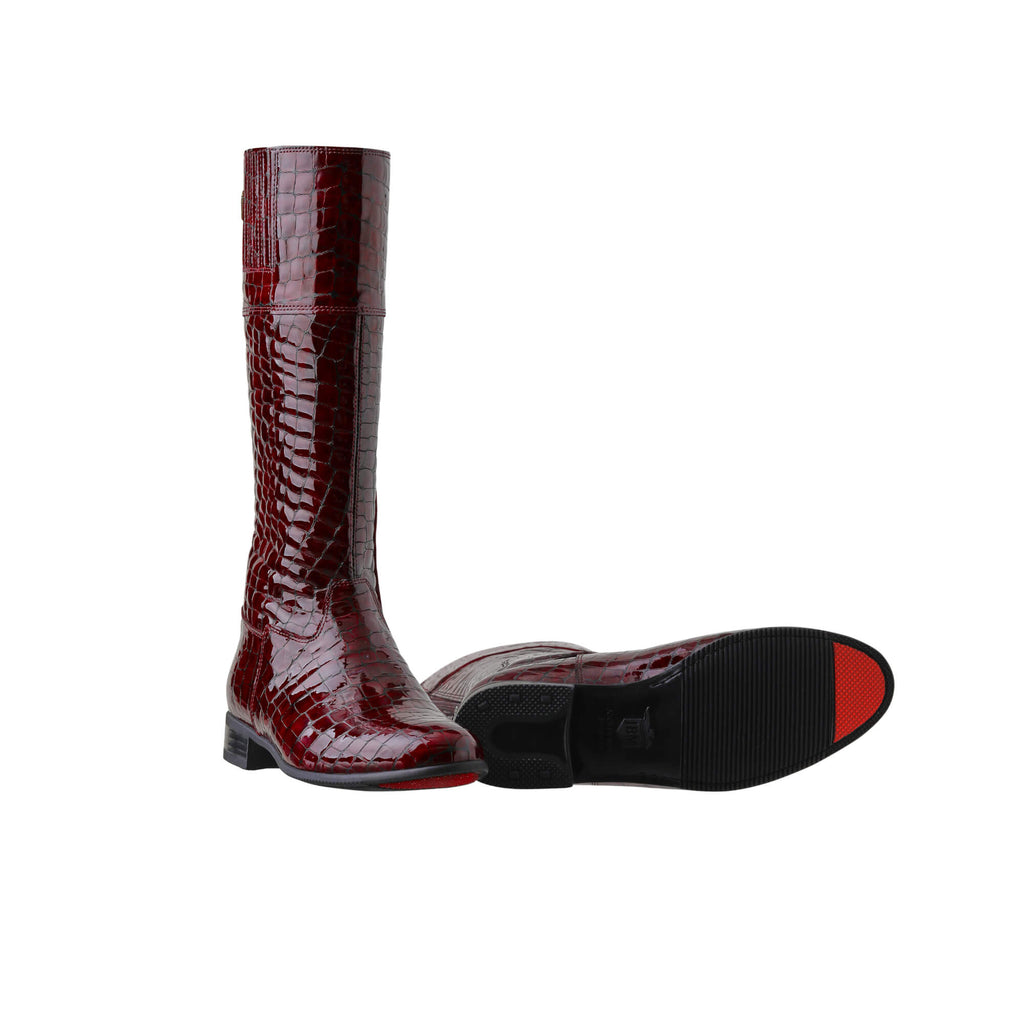  Image of tall burgundy crocodile leather boots against a white background. One boot is positioned sole down with the zipper done, while the other boot is laid down to showcase its sole, which features a red tip design. The boots also feature a back zip and a 1.5-2cm stretch feature on the calf area.