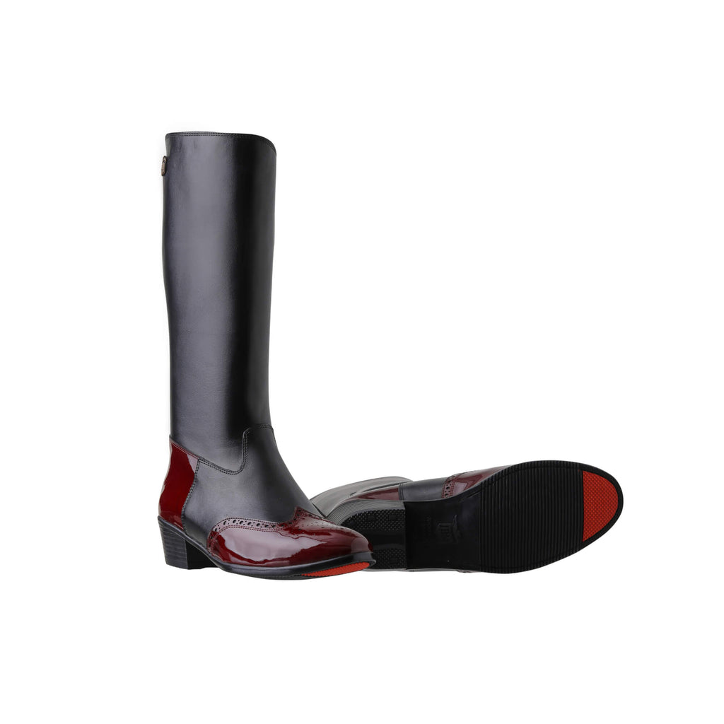 A pair of tall black leather Cuban heel boots with burgundy wingtip accents. The boots feature a back zip and are displayed against a white background. One boot is positioned sole down with the zipper done, while the other boot is laid down to showcase the sole, which features a red tip design.